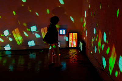 person standing in a dark room with many projected lights