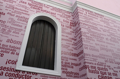 red words and phrases on pink building façade, hard to read